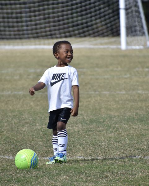 छोटा लड़का फुटबॉल खेल रहा है
